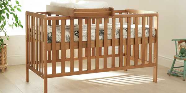 An oak cot bed in a nursery.